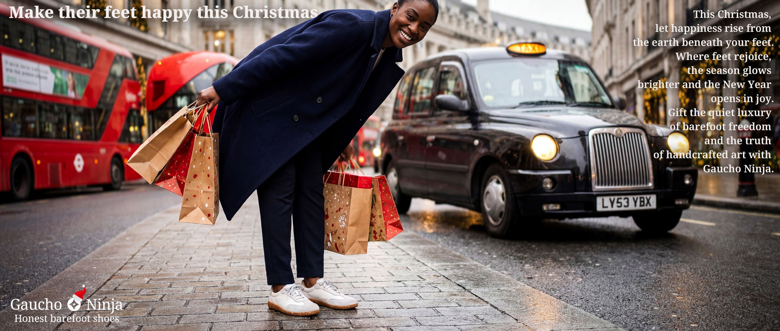 woman with Christmas shopping bags standing on a London street with a black taxi and red buses in the background wearing Gaucho Ninja barefoot trainers