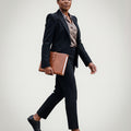 Woman in a professional outfit holding a folder wearing Goodyear welted barefoot brogue shoes in black leather