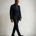 Man in a black suit wearing Goodyear welted barefoot brogue shoes in black leather