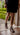 Person wearing a black skirt and goodyear welted barefoot boots in brown leather, standing on a stone path with greenery in the background, best women barefoot dress boots
