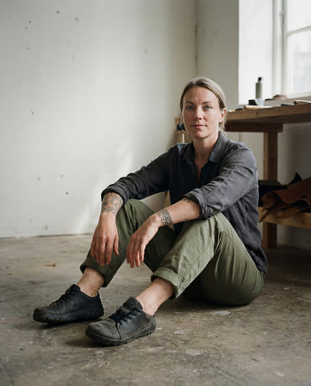 Person sitting on the floor in a room with a table and window in the background wearing barefoot safety trainers by Gaucho Ninja